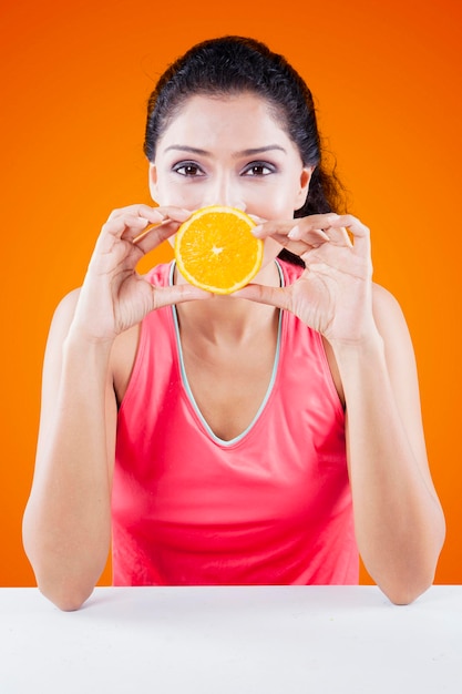 Mulher cobrindo a boca com fruta laranja