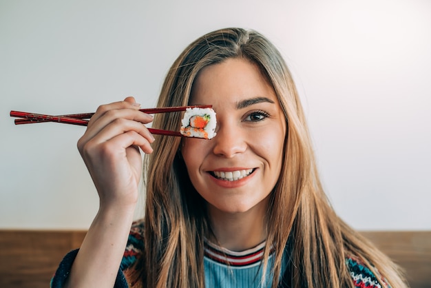 Mulher cobrindo o olho com um pedaço de sushi