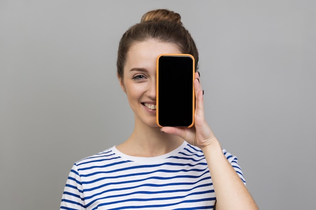 Mulher cobrindo os olhos com celular com display vazio para propaganda