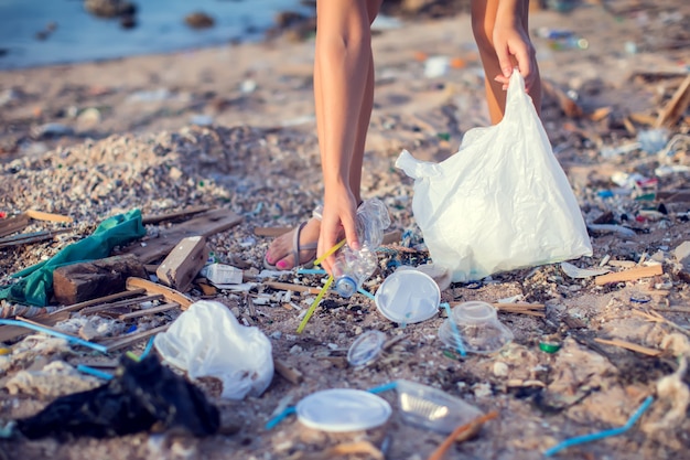 Mulher coleta lixo na praia. Conceito de proteção ambiental