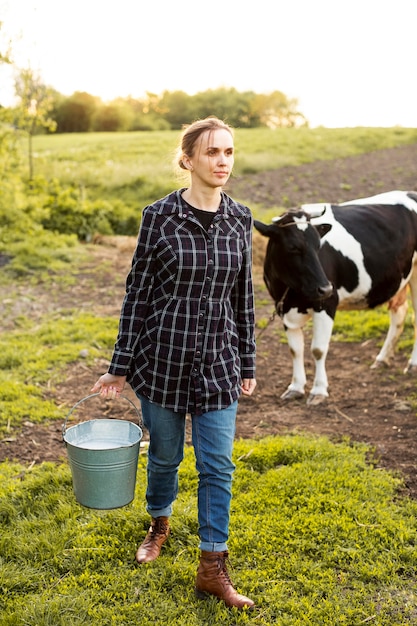 Mulher coletando leite de vaca