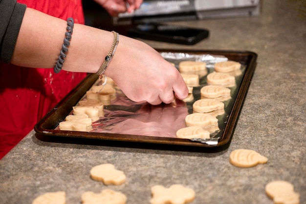 Mulher coloca biscoitos na assadeira Preparando deliciosos biscoitos caseiros Mulher assa refeição em casa