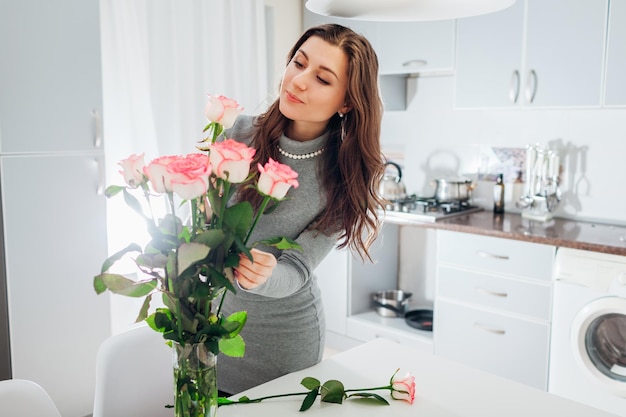 Mulher coloca rosas em vaso dona de casa cuidando do aconchego na cozinha moderna cozinha design