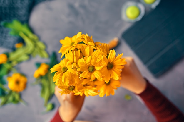 Foto mulher coloca um crisântemo amarelo flores em um vaso de vidro transparente na mesa loft