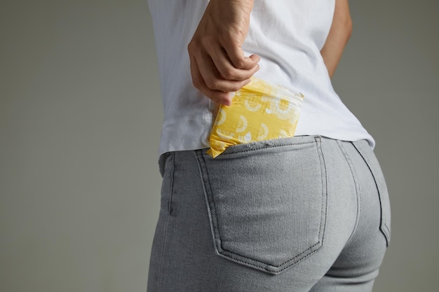 Mulher colocando absorvente no bolso da calça jeans