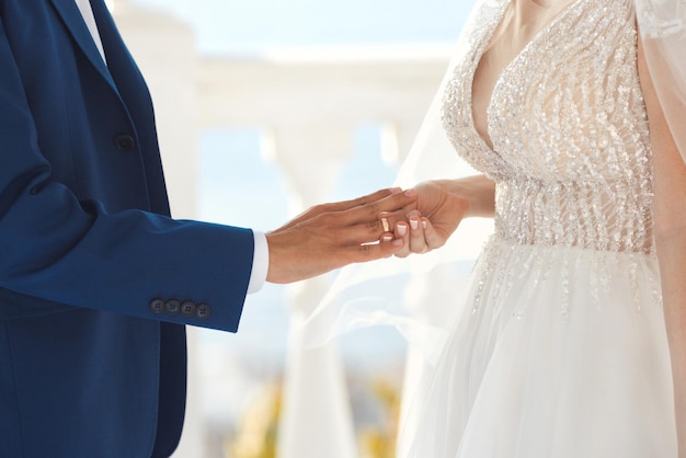 Mulher colocando anel de noivado na mão do homem na cerimônia de casamento
