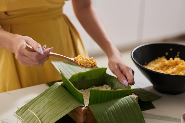 Mulher colocando colher de recheio no bolo de arroz pegajoso