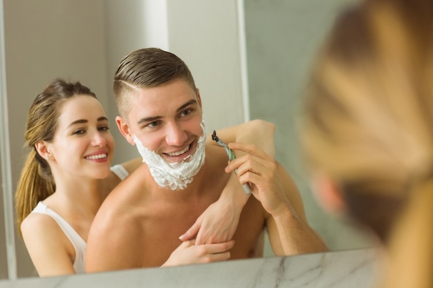 Mulher colocando espuma de barbear no rosto dos namorados