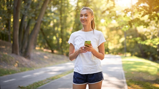 Mulher colocando fones de ouvido para ouvir música antes de correr no parque de verão