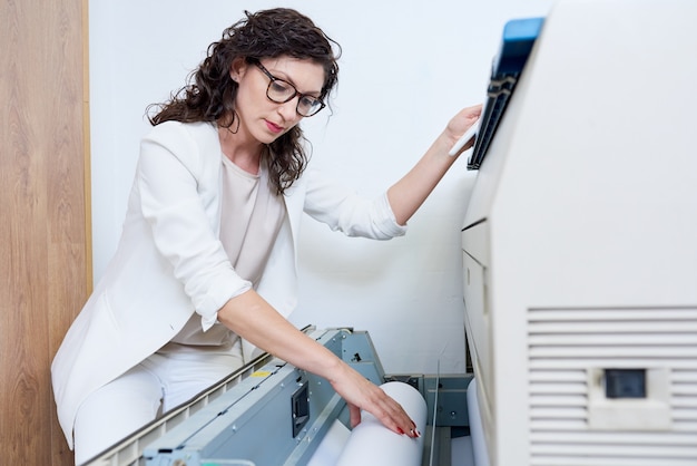 Mulher colocando papel na impressora