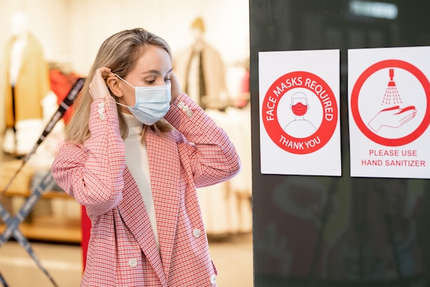 Foto mulher colocando uma máscara ao entrar no shopping