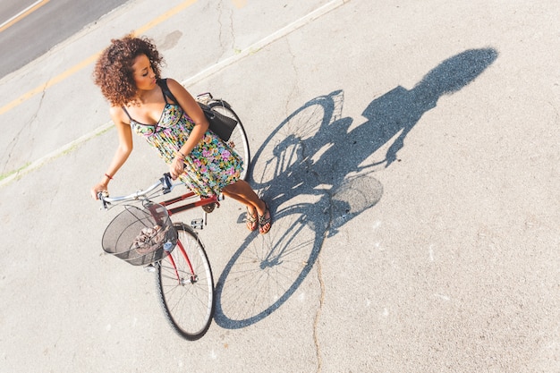 Foto mulher com a bicicleta com sua sombra na estrada.