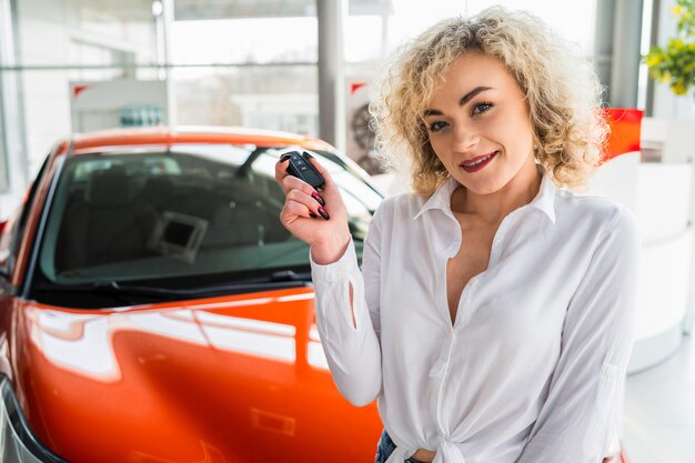 Mulher com a chave nas mãos perto do carro