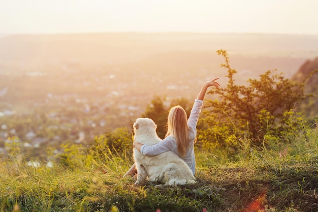 mulher com a mão para cima e seu cachorro golden retriever na colina