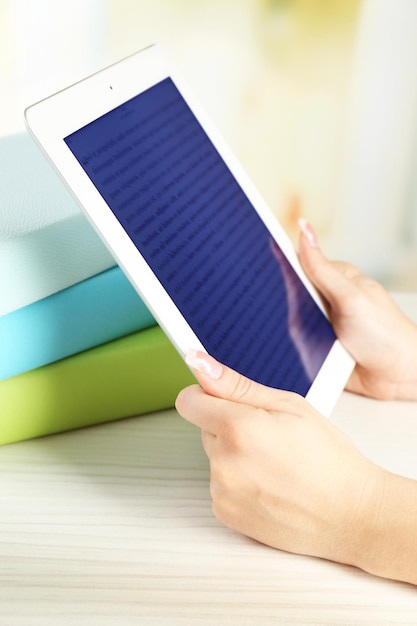 Foto mulher com a mão segurando um tablet de pc perto de livros em close-up conceito de educação moderna