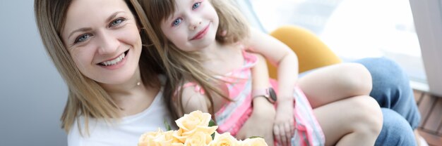 Mulher com a menina de joelhos segurando um buquê de flores. conceito de dia das mães