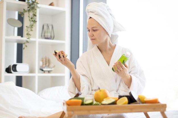 Mulher com abacate escaneando produtos para a pele no quarto