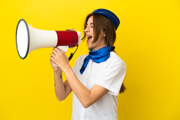 Mulher com aeromoça isolada em um fundo amarelo gritando através de um megafone