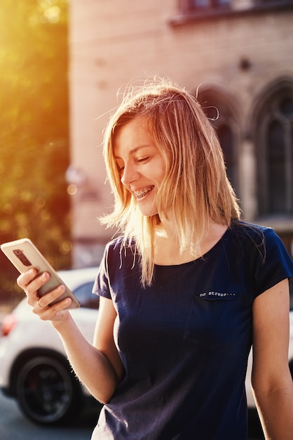 Mulher com aparelho ortodôntico usando smartphone em rua da cidade