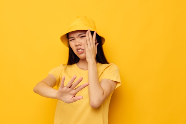 Mulher com aparência asiática em uma camiseta amarela e chapéu posando emoções tiro monocromático