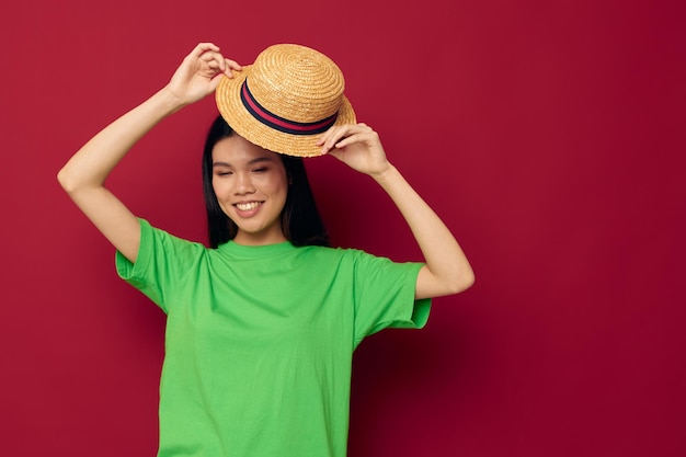 Mulher com aparência asiática sorri chapéu de camiseta verde posando fundo isolado de moda inalterado