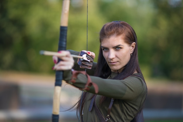 Foto mulher com arco e flecha atirando na floresta