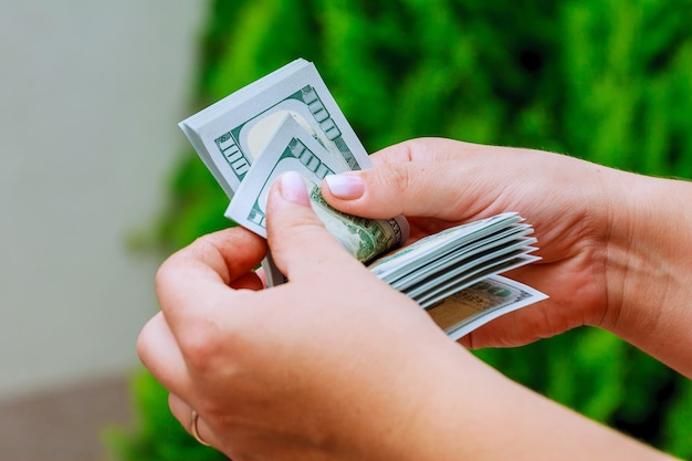 Mulher com as mãos contando notas de dólar. gastar dinheiro.