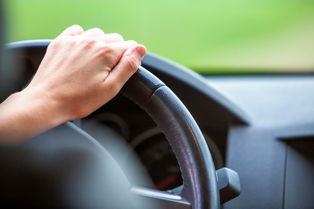 Foto mulher com as mãos no volante dirigindo um carro.