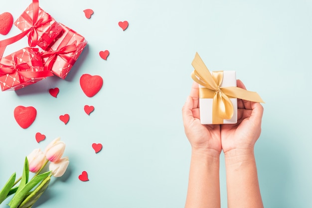 Mulher com as mãos segurando uma caixa de presente ou presente decorada e um coração vermelho surpresa