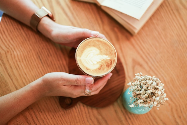 Mulher com as mãos segurando uma xícara de café com latte art. segurando uma xícara de chá ou café da manhã.