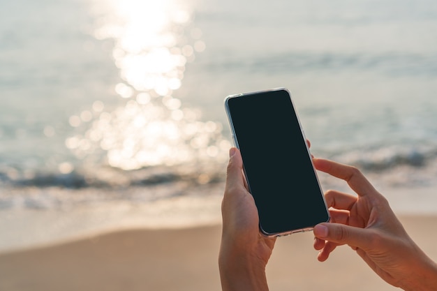 mulher com as mãos usando telefone celular na praia. conceito de negócios, tecnologia, viagens e estilo de vida.