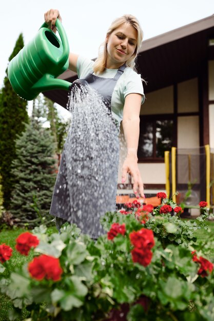 Foto mulher com avental regando flores no jardim