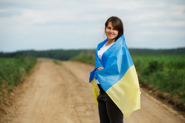 Mulher com bandeira ucraniana no campo de trigo menino feliz comemorando o dia da independência