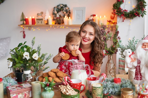 Mulher com bebê na cozinha decorada para o Natal.