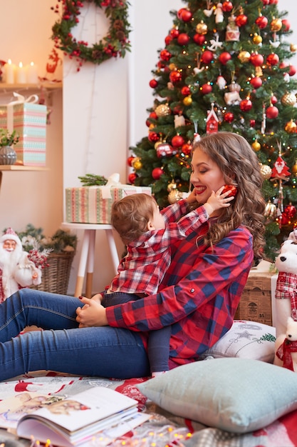 Mulher com bebê na cozinha decorada para o Natal.