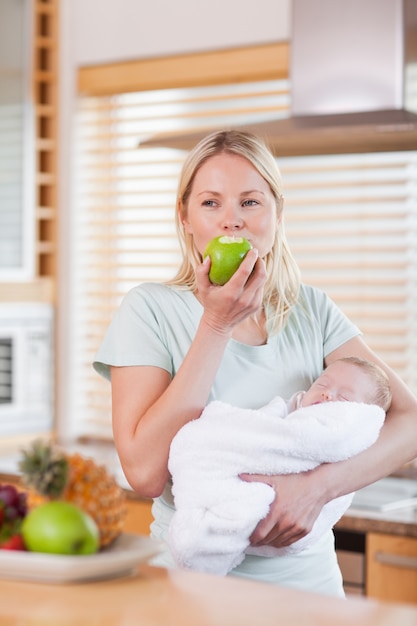 Mulher com bebê nos braços com uma maçã