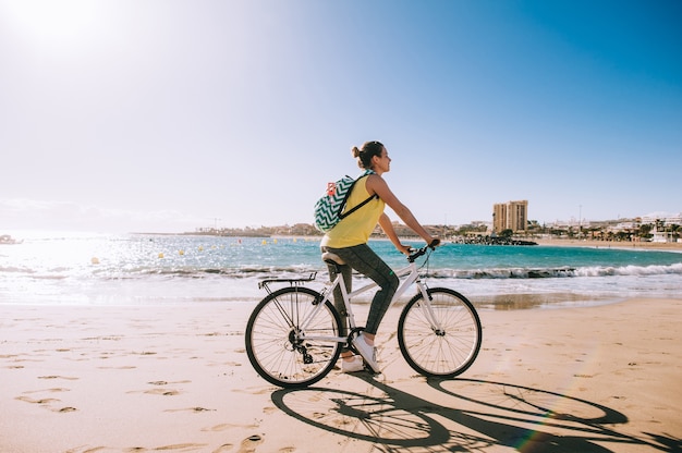 Mulher com bicicleta na praia