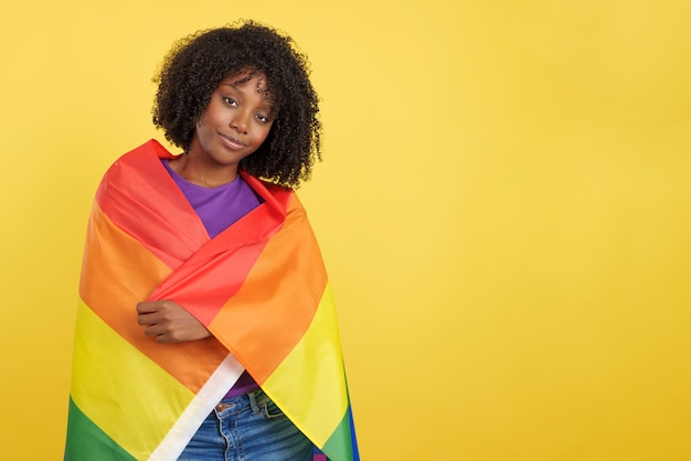 Foto mulher com cabelo afro envolto em uma bandeira lgbt