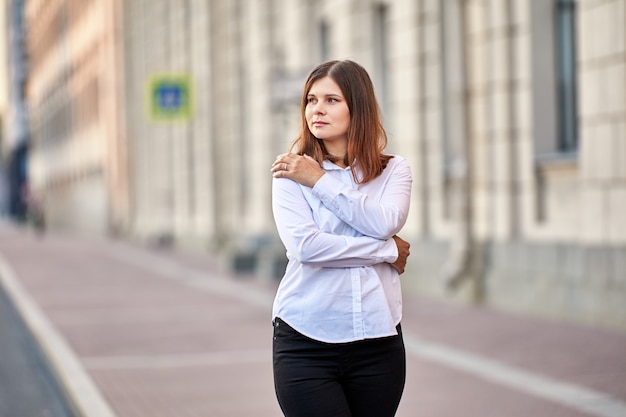 Mulher com cabelo castanho com camisa fica na rua