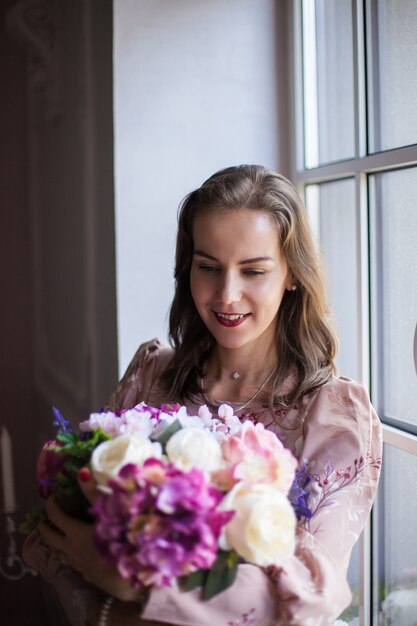 Mulher com cabelo castanho e lábios vermelhos com um vestido rosa