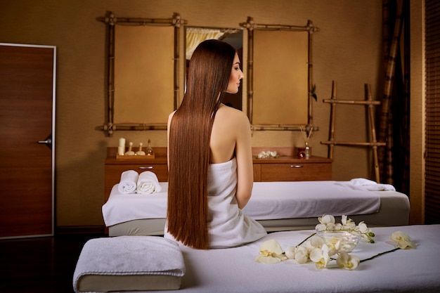 Mulher com cabelo comprido lindo sentada na cadeira de massagem no spa s