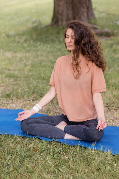 Mulher com cabelo encaracolado medita em um parque de ioga e meditação para saúde mental e física