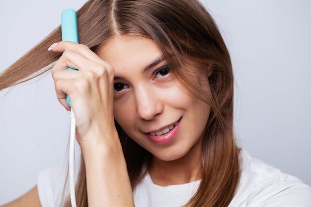 Mulher com cabelo longo e reto bonito usando alisador de cabelo.