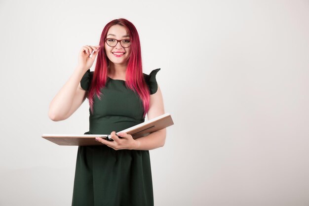 Mulher com cabelo rosa em branco segurando o livro