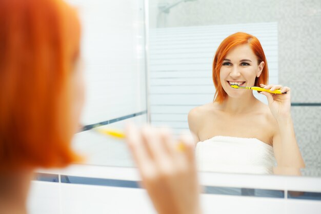 Mulher com cabelo vermelho no banheiro usar produtos de cuidados