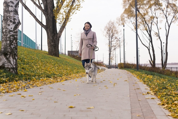 Mulher com cachorro andando no parque costeiro de outono