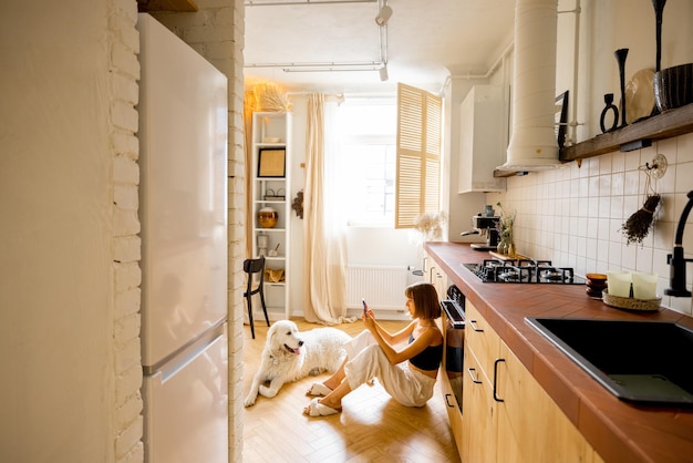 Mulher com cachorro na cozinha moderna e elegante