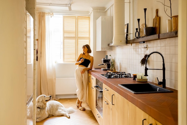 Foto mulher com cachorro na cozinha moderna e elegante