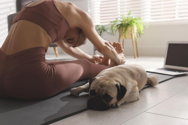 Foto mulher com cachorro seguindo aula de ioga online em casa