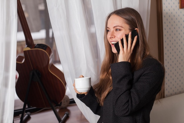 Mulher com café atrás de guitarra e bebendo